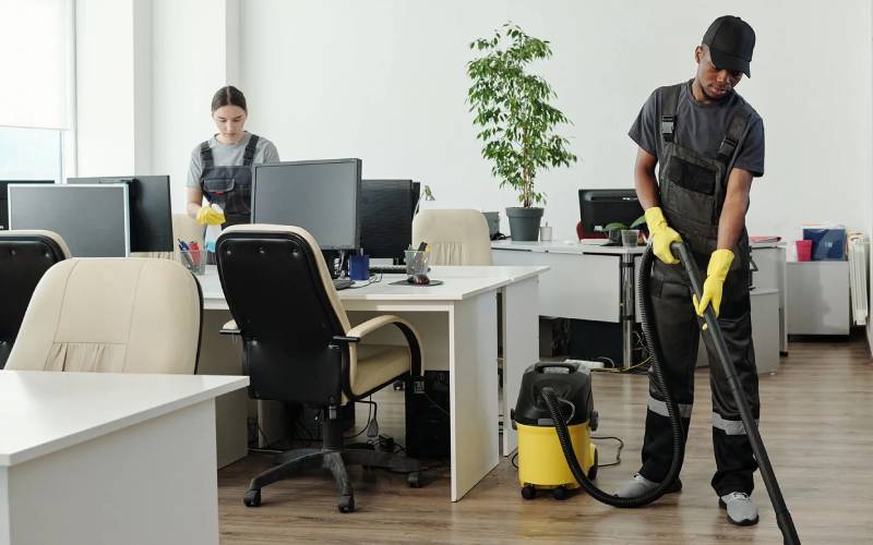 Professional cleaning team vacuuming and cleaning an office