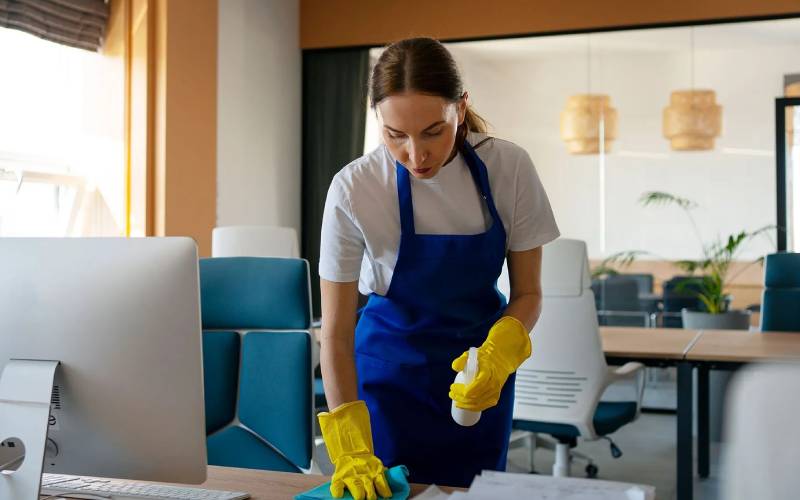Professional cleaner deep cleaning an office workstation
