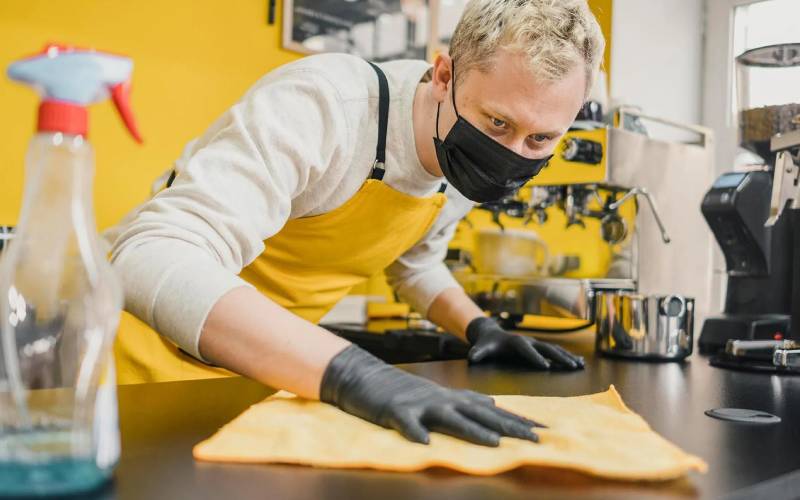 Professional cleaner wiping surfaces in a commercial kitchen