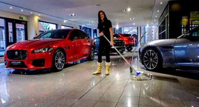 Professional cleaner mopping a car dealership showroom