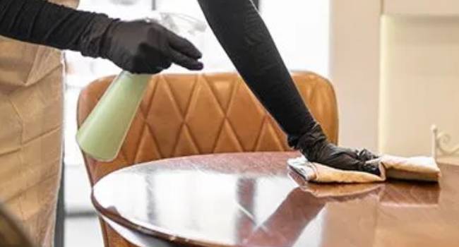 Professional cleaners wiping tables in a dining or breakroom area
