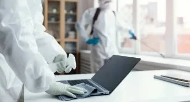 Professional cleaner disinfecting office equipment and surfaces