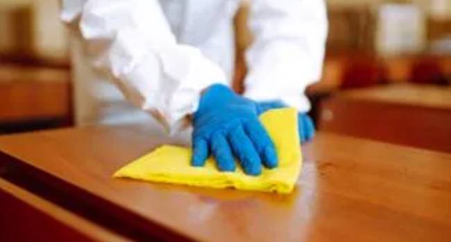 Professional cleaner wiping a church pew