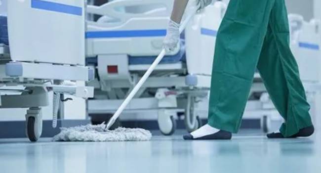 Healthcare cleaning staff mopping and sanitizing a hospital floor
