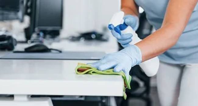 Professional cleaner wiping an office desk in Norwalk
