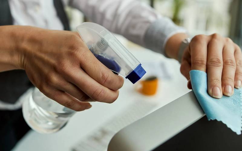 Professional cleaner disinfecting office computer equipment