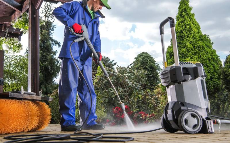 Professional cleaner power washing an outdoor patio surface