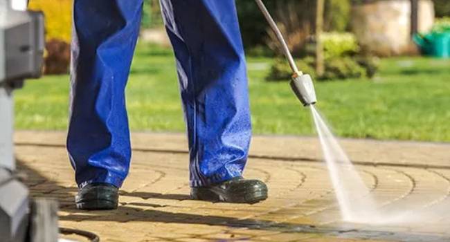 Professional cleaner power washing an outdoor commercial surface