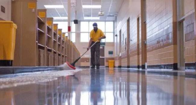 Professional cleaner mopping a school hallway