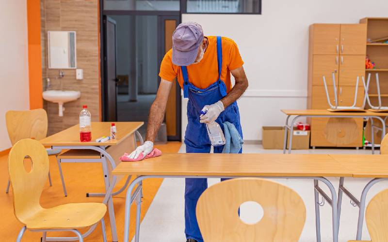 Professional cleaning staff disinfecting a school classroom