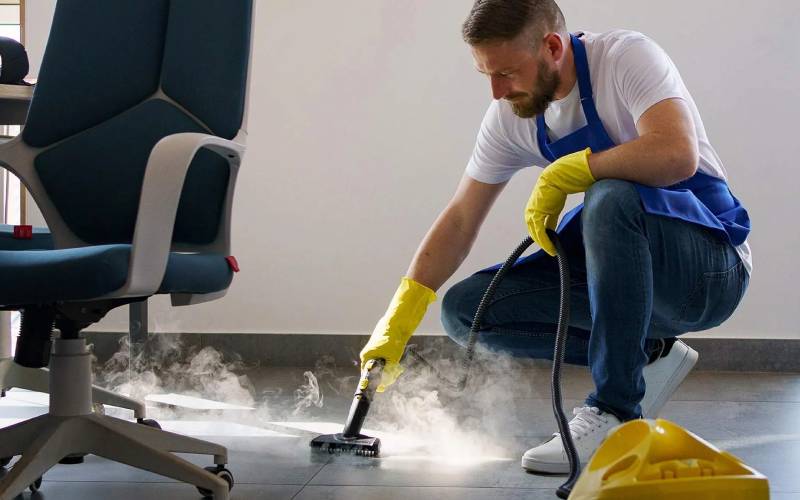 Professional cleaner steam cleaning tile and grout in a commercial space